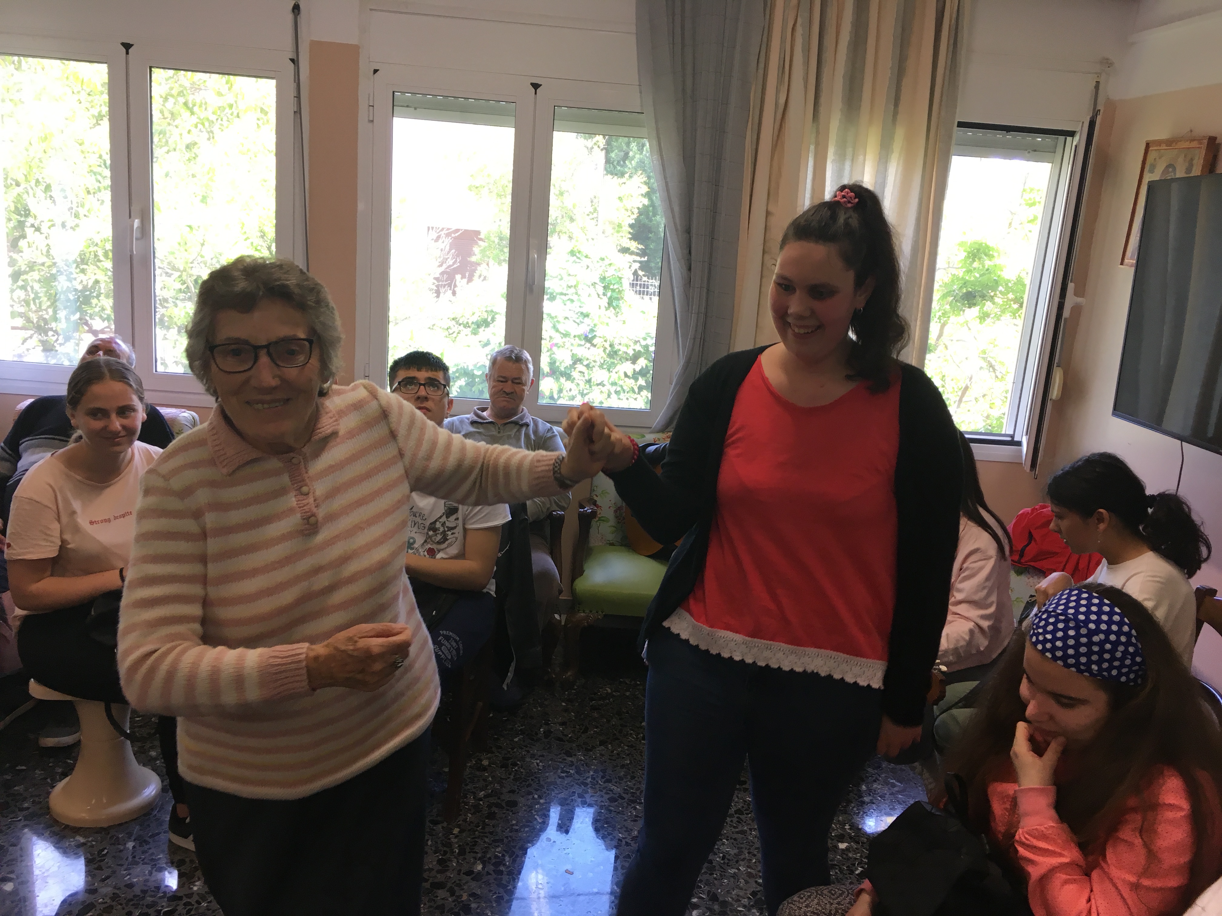 Μία κυρία ηλικιωμένη πιασμένη χέρι χέρι με μία μαθήτρια του ΚΕΑΤ με πρόβλημα όρασης